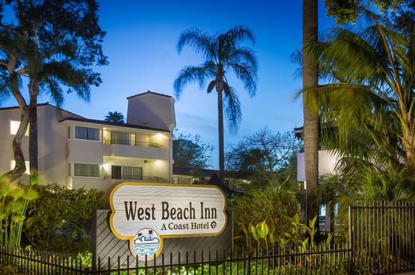 View of The West Beach Inn, a Coast Hotels' sign among some palm