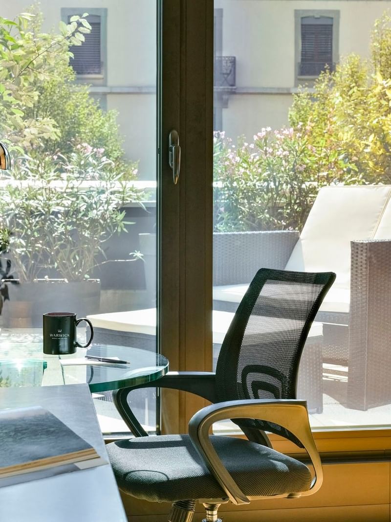 Office chair by a glass desk under a silver lamp in Deluxe Terrace Room at Warwick Geneva