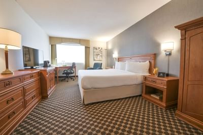 King bed, dresser and desk with chair by window.