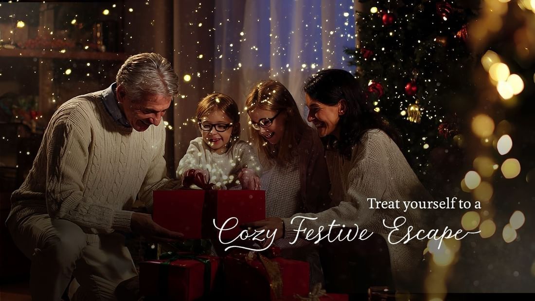 Family of four opening gifts near a Christmas tree with festive lights and text.