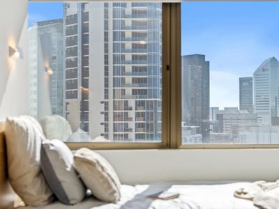 Bedroom with city view through a large window at UniLodge Brisbane City.