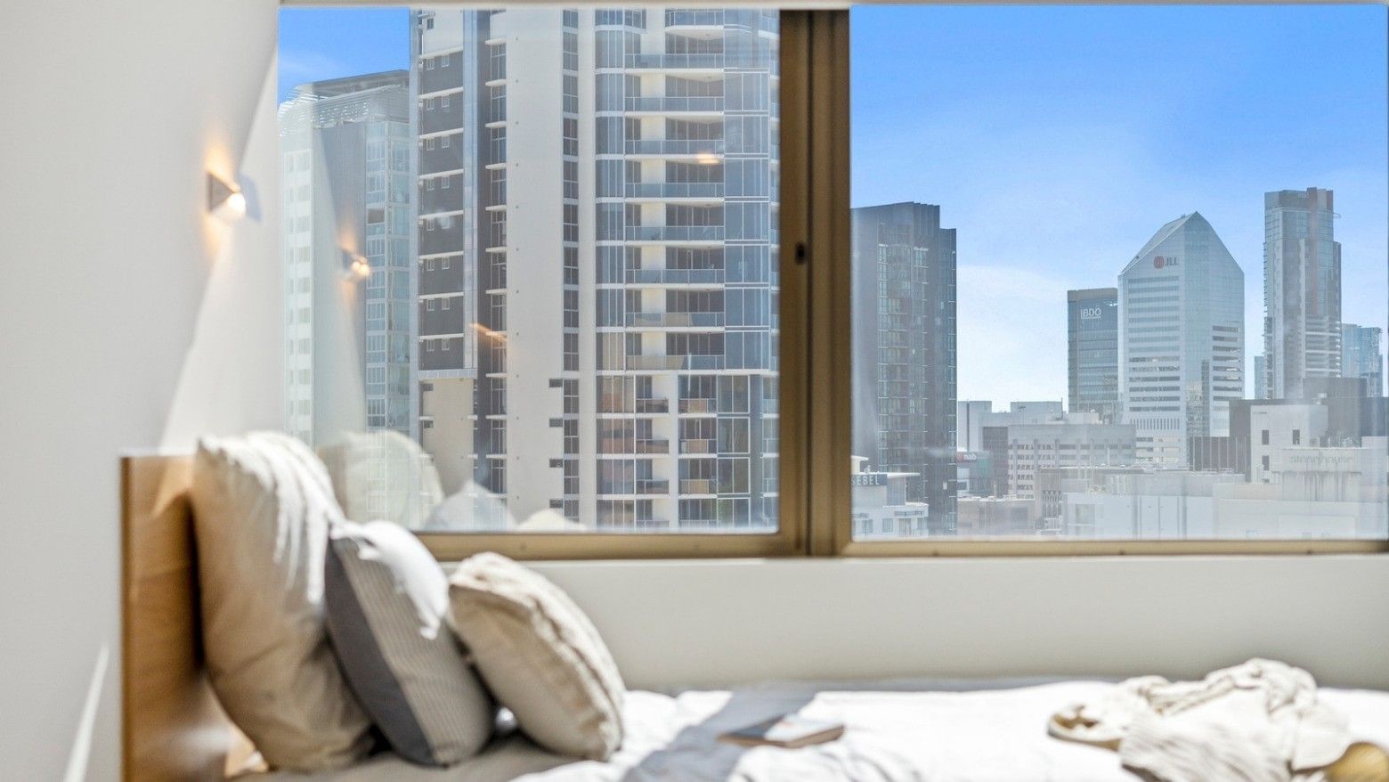 Bedroom with city view through a large window at UniLodge Brisbane City.