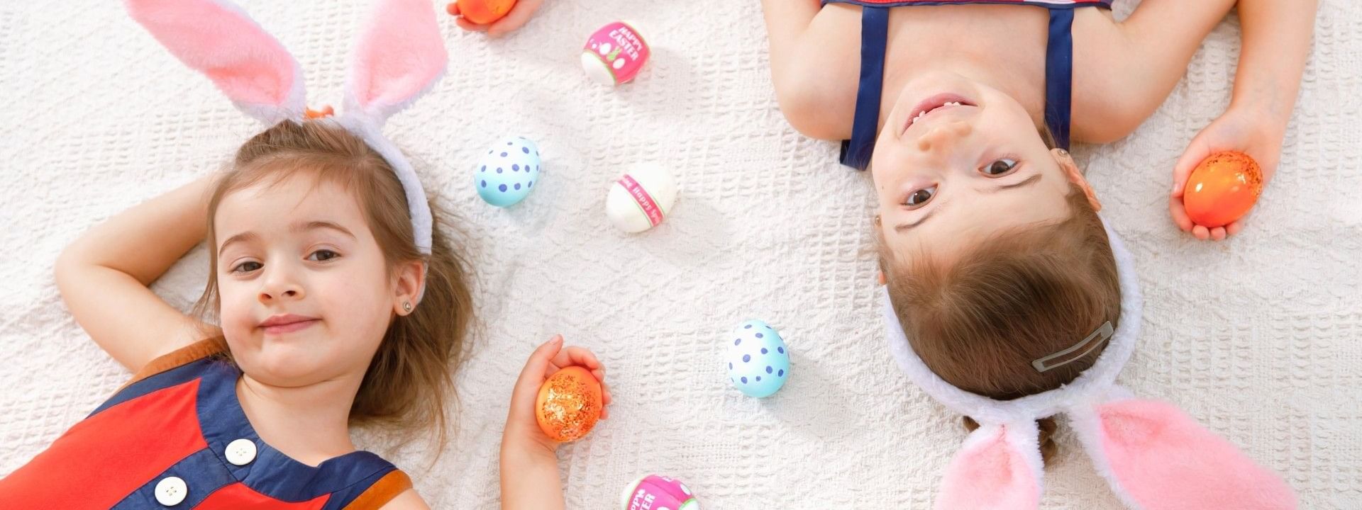 Two children with Easter bunny ears and with colourful eggs promoting Easter Accommodation Package.