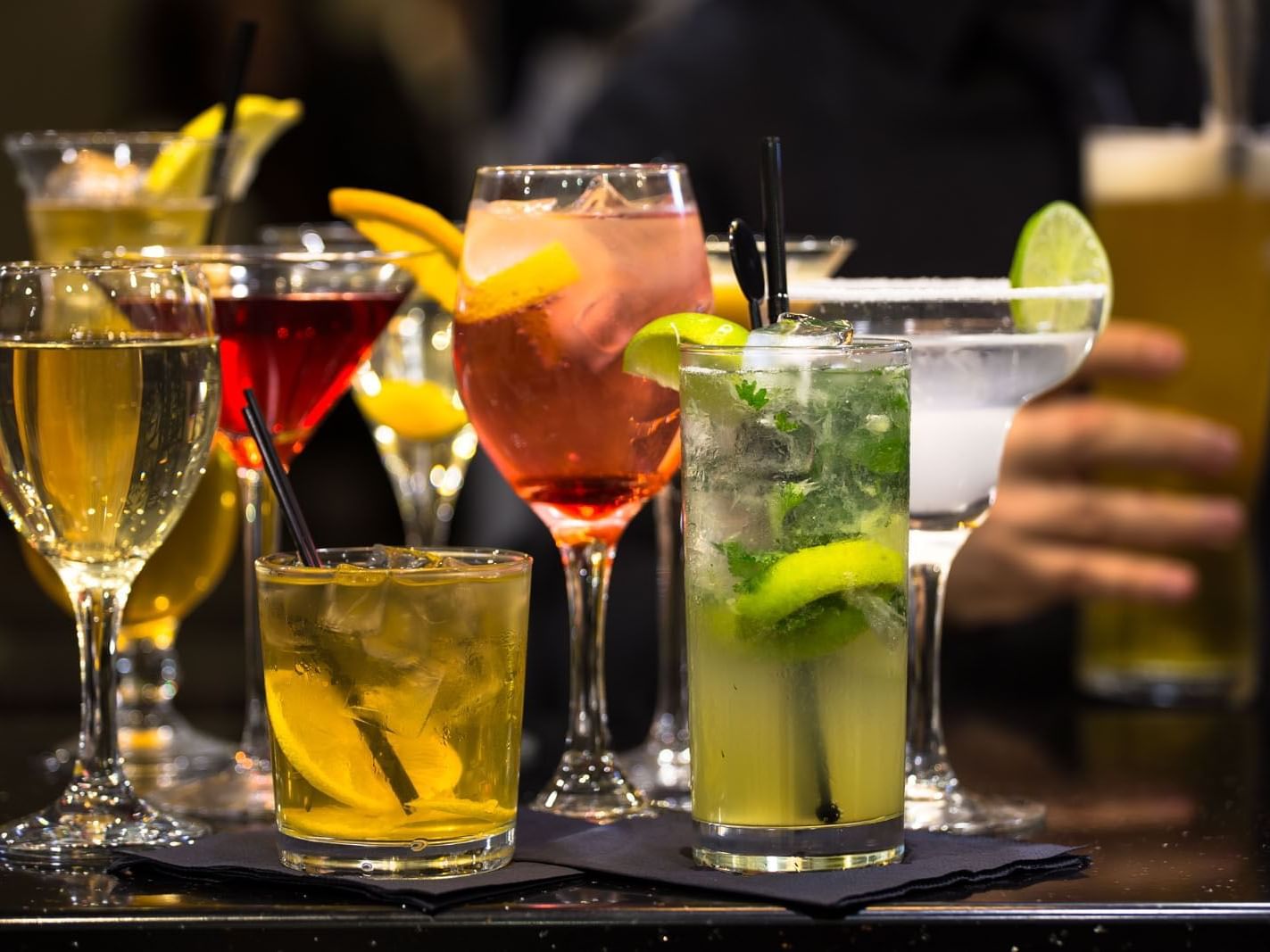 Colorful cocktails with lemon lime and mint garnishes arranged on a bar counter at Heston Hyde Hotel