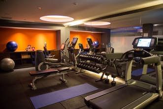 Gym with treadmills & weights by an orange wall at The J House Greenwich, a modern boutique hotel in Greenwich Connecticut