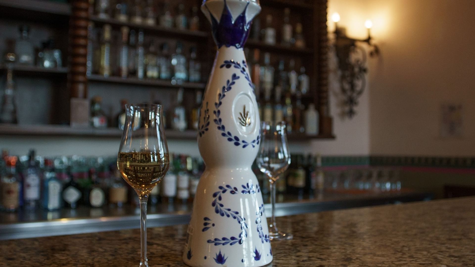A decorative bottle and glasses of amber tequila on Bar La Suerte at Hacienda del Mar Los Cabos