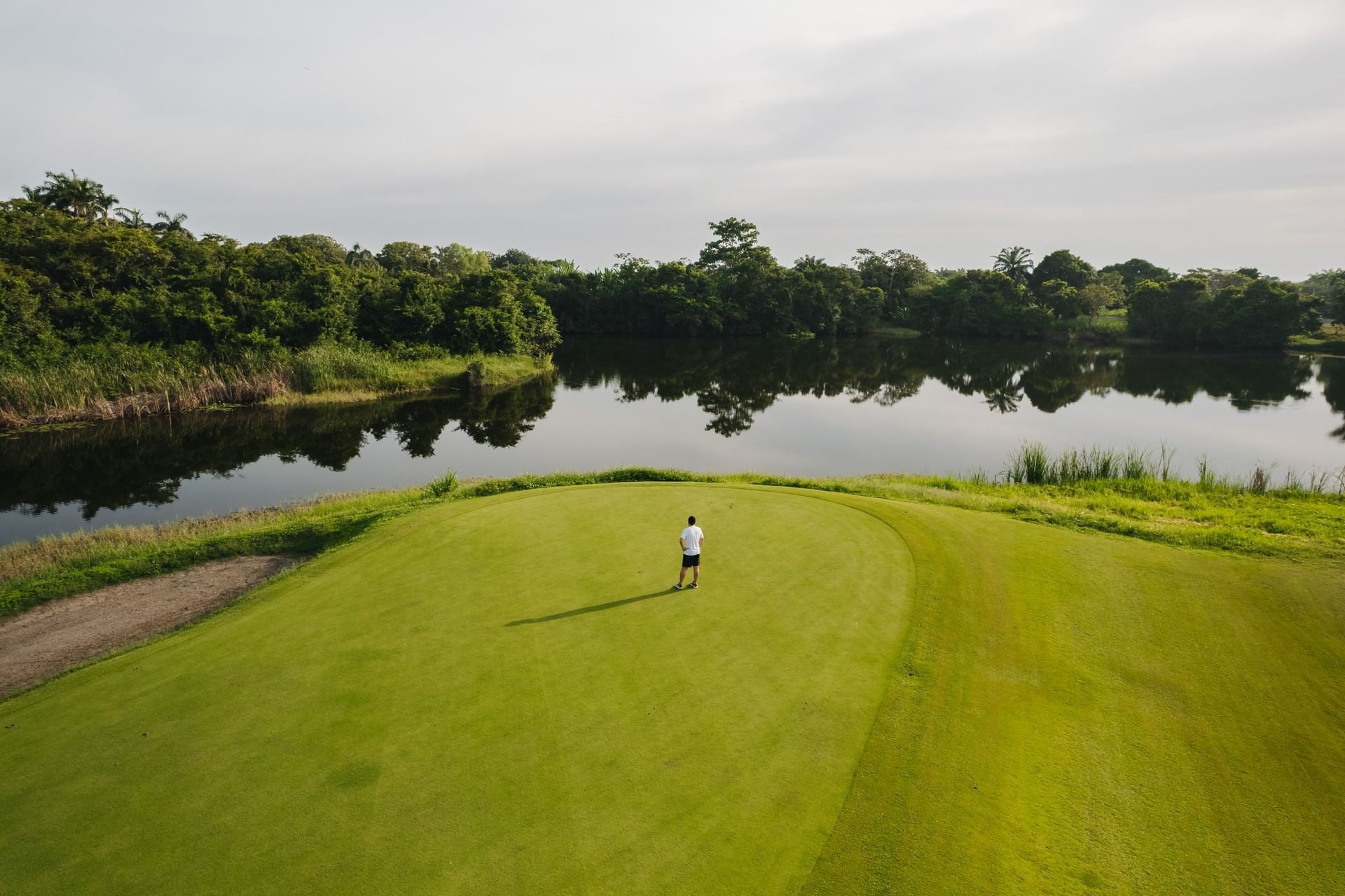Man walking on a golf course surrounded by water near Indura Beach & Golf Resort