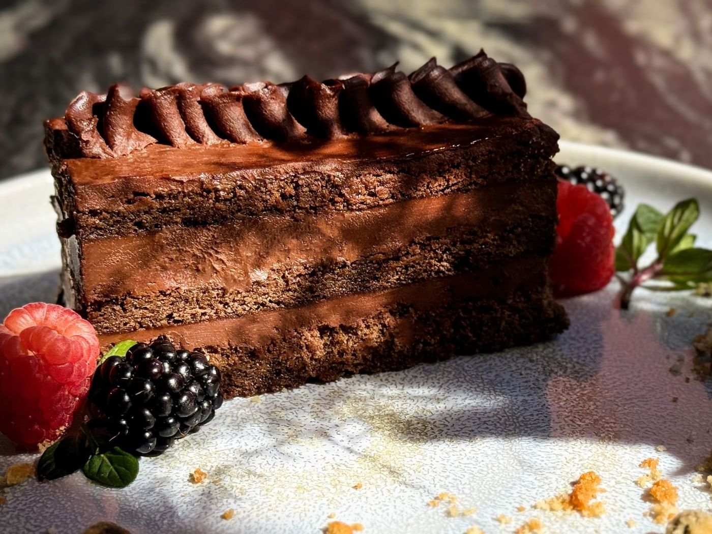 Close-up of a slice of chocolate cake served with berries in Deli Station at Grand Fiesta Americana