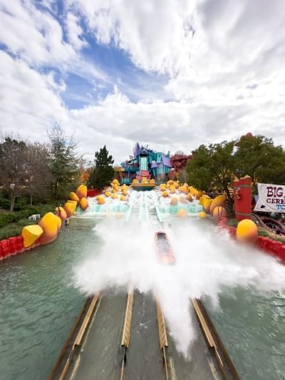 A log on a track creates a big splash below waterfalls laden with big yellow boulders. 