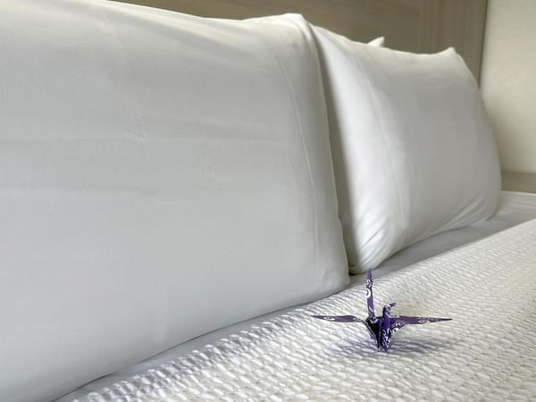 Coast Premium Queen bed with white linens and decorative origami crane at Coast Calgary University Area Hotel by APA