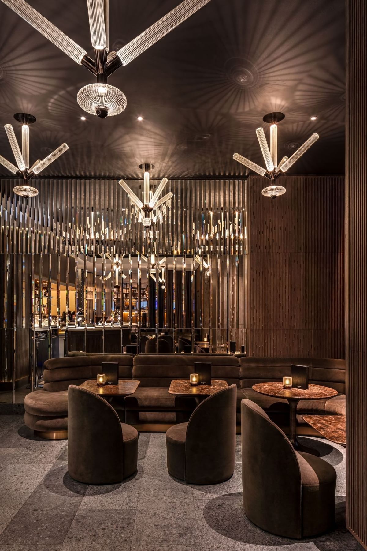 Chic lounge at The May Fair Bar featuring plush seating, round tables, orb lights, and warm tones with ambient lighting