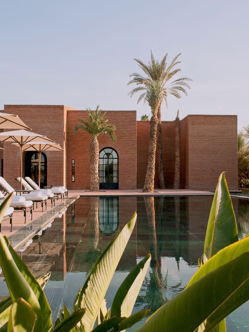 Sun loungers with patio umbrellas by the pool deck at the Chenot Spa of Selman Marrakech