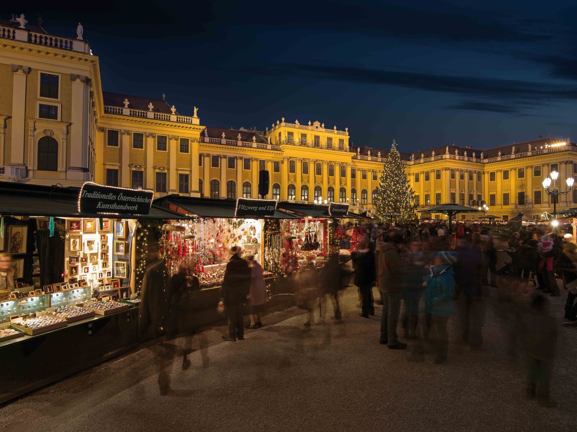 Christmas market in front of Schönbrunn Palace in Vienna at night with illuminated palace, Christmas tree and festive market stalls
