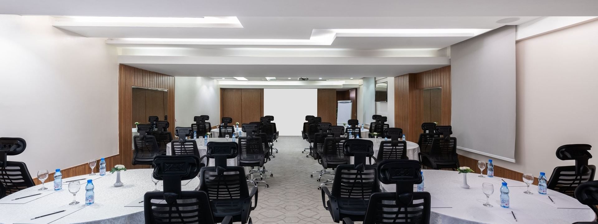 Cabaret set-up with black mesh chairs facing the projector screen in Meeting Room C (A+B) at Warwick Hotel Jeddah