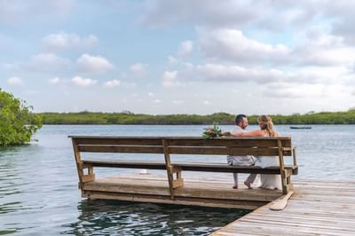 Couple sitting on a wooden dock bench by the water at Barefoot Cay Resort & Marina