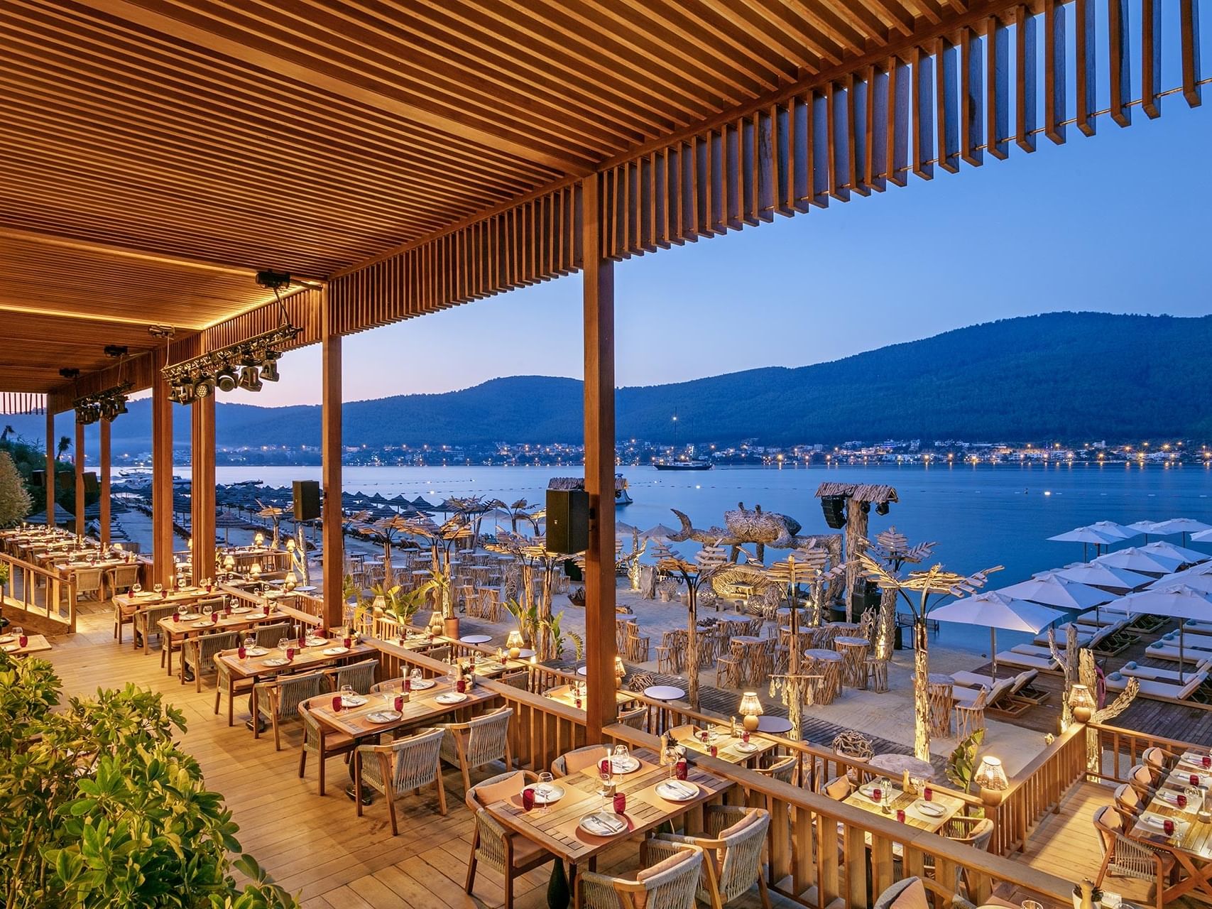 Seafront open-air restaurant at Titanic Luxury Collection Bodrum, glowing in the evening light.