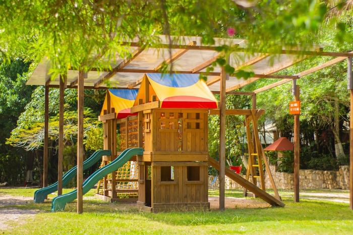 Kids play area with slides & climbing nets under a canopy, surrounded by tropical greenery at Hotel Chan-kah Resort Village