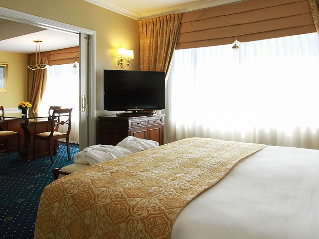 A bed, TV & sitting area at a suite in Hotel Emperador Buenos