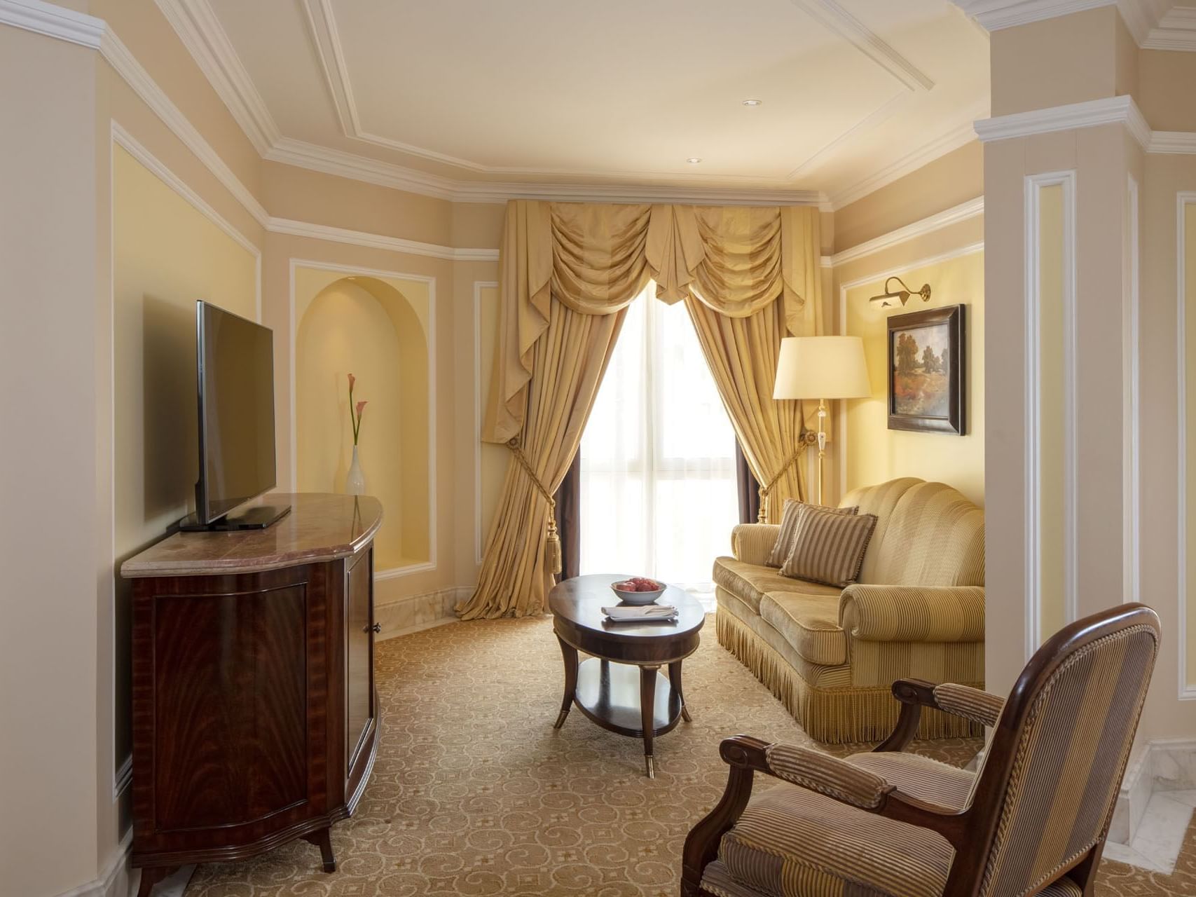 Living area with a TV & couch in Junior Suite at Regency Hotel