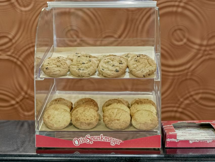 Assorted chocolate chip cookies in a clear display case by a red napkin box at Galleria Palms Hotel 