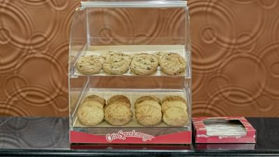Assorted chocolate chip cookies in a clear display case by a red napkin box at Galleria Palms Hotel 