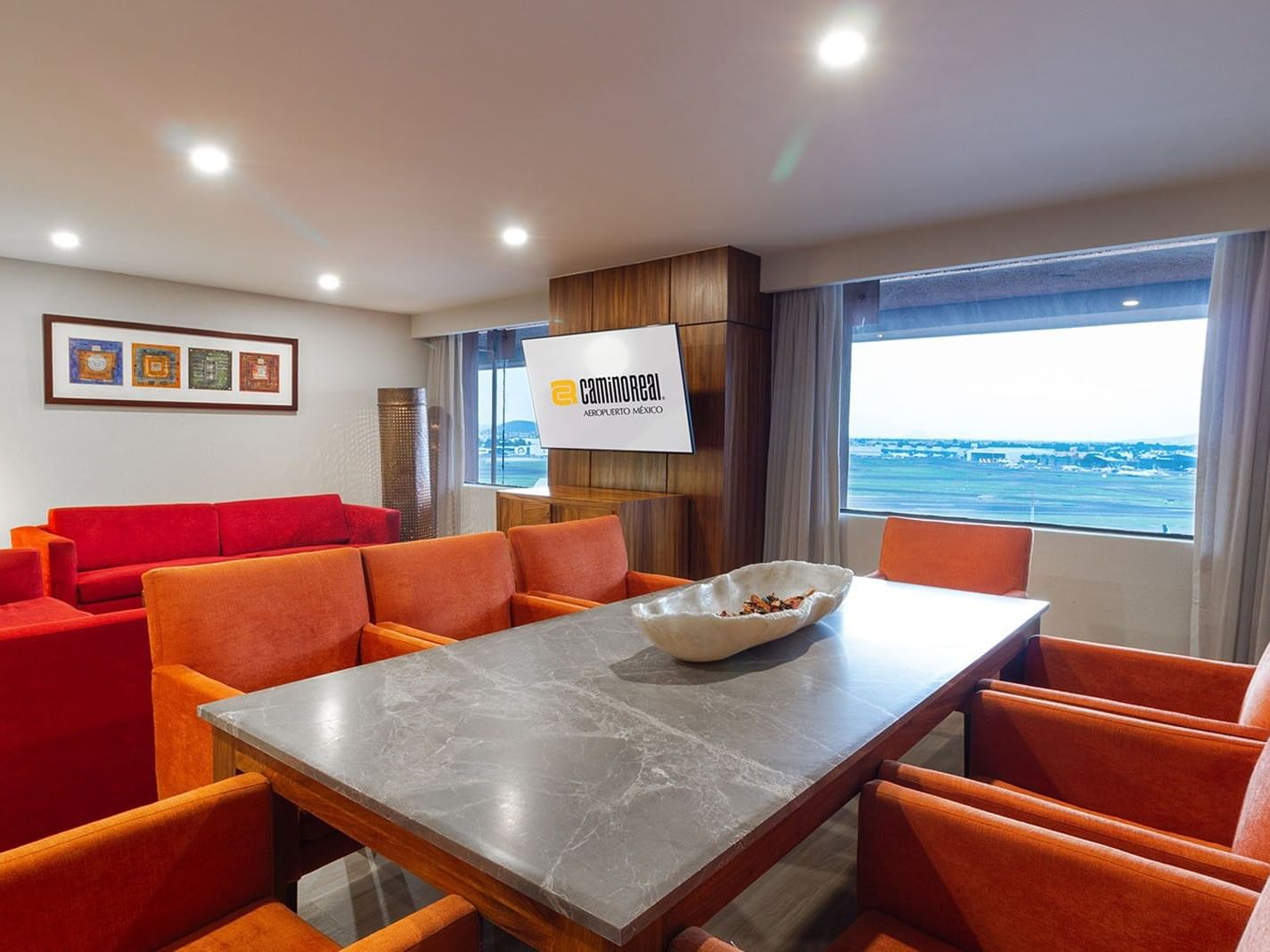 Sala de estar de la Master Suite King con sofás rojos y vistas al aeropuerto en Camino Real Aeropuerto México, Ciudad de México