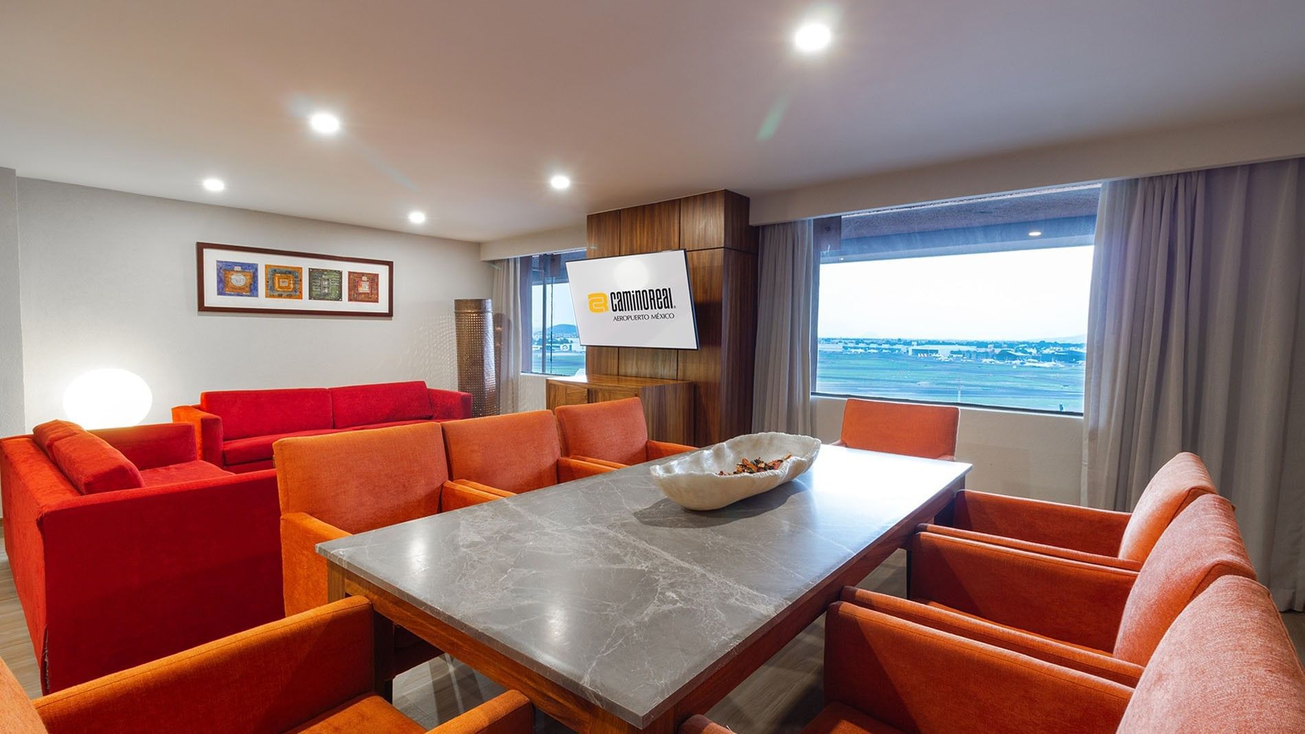 TV lounge with plush sofa and dining table by the window in the King Master Suite at Camino Real Aeropuerto Mexico