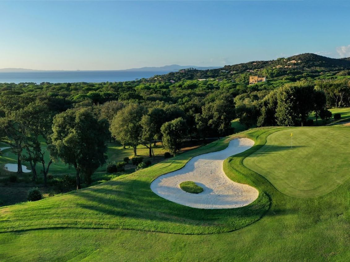 Aerial view of the Golf Course surrounded by lush green forest at Golf Hotel Punta Ala