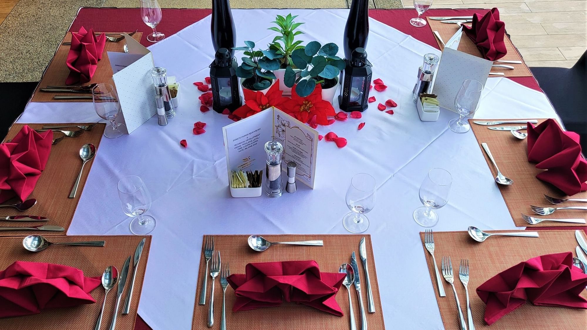Elegant dining table set with red napkins, petals, menus, and wine glasses at Sunway Hotel Big Box