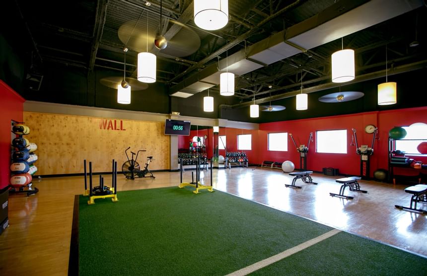 Training area with green turf and sleds beside benches and kettlebells in Miami Lakes Athletic Club at Miami Lakes Hotel