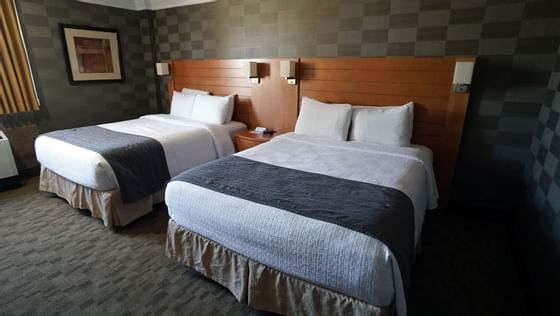 Double beds with a wood headboard, beside a nightstand, in Garden Standard at Glenmore Inn & Convention Centre