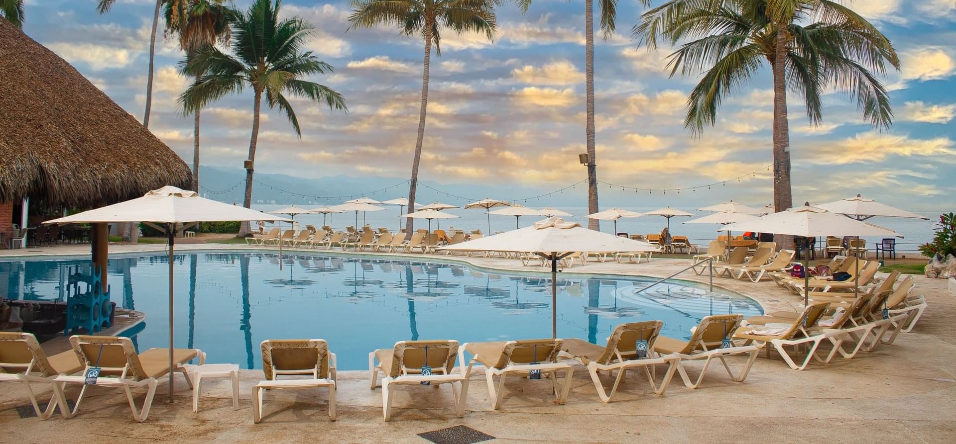 A outside pool surrounded by lounge chairs and umbrellas at Plaza Pelicanos Club Beach Resort