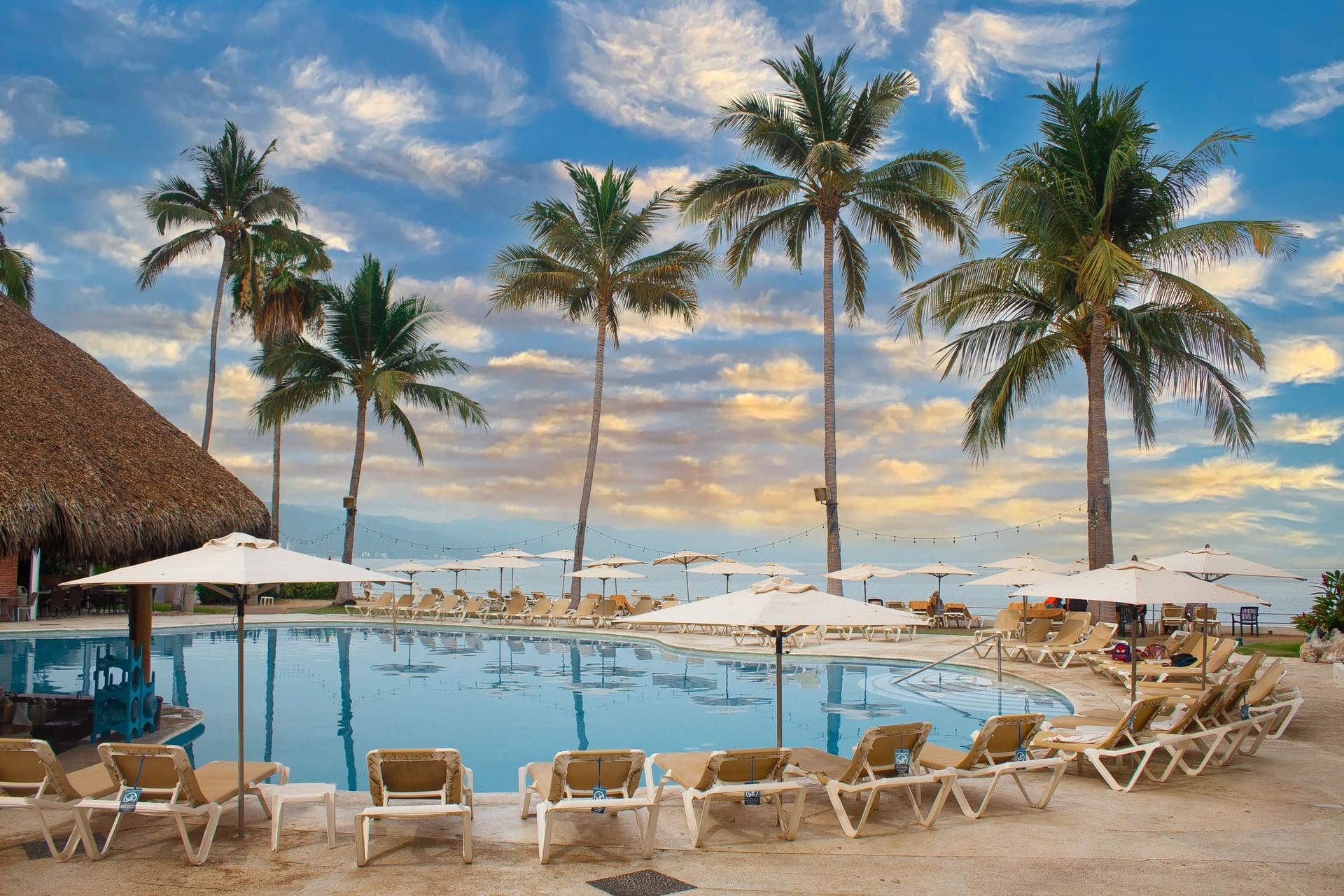 A outside pool surrounded by lounge chairs and umbrellas at Plaza Pelicanos Club Beach Resort