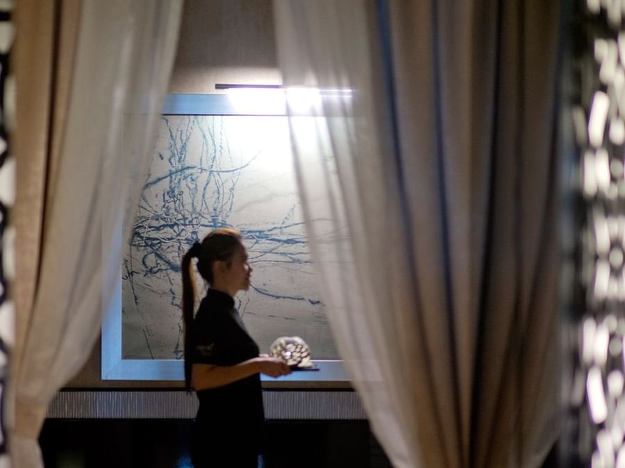Lady standing by a window with sheer curtains in a spa near DAMAC Hotels & Resorts, the best spa hotels in Dubai