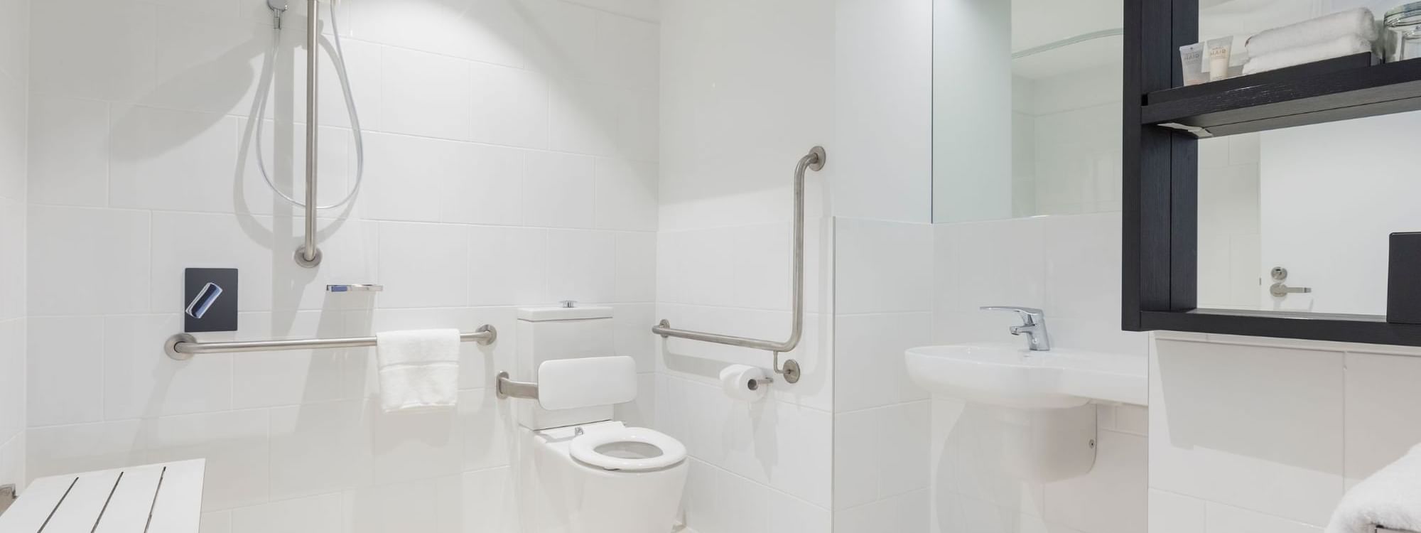 Special Access Room bathroom featuring a walk-in shower, support rails, and a fold-down seat at Ibis Adelaide