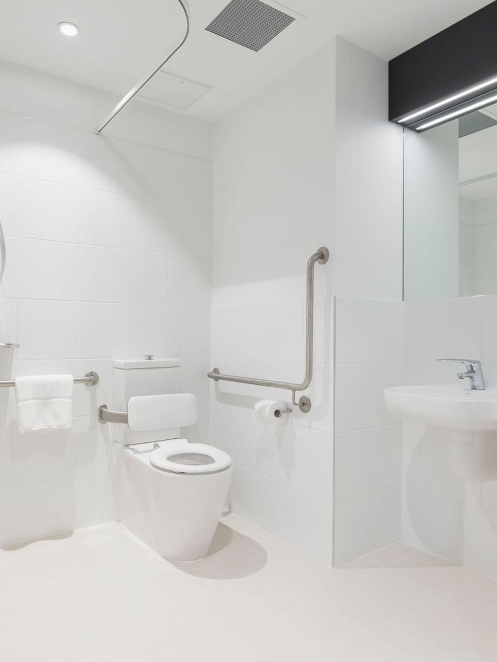Special Access Room bathroom featuring a walk-in shower, support rails, and a fold-down seat at Ibis Adelaide