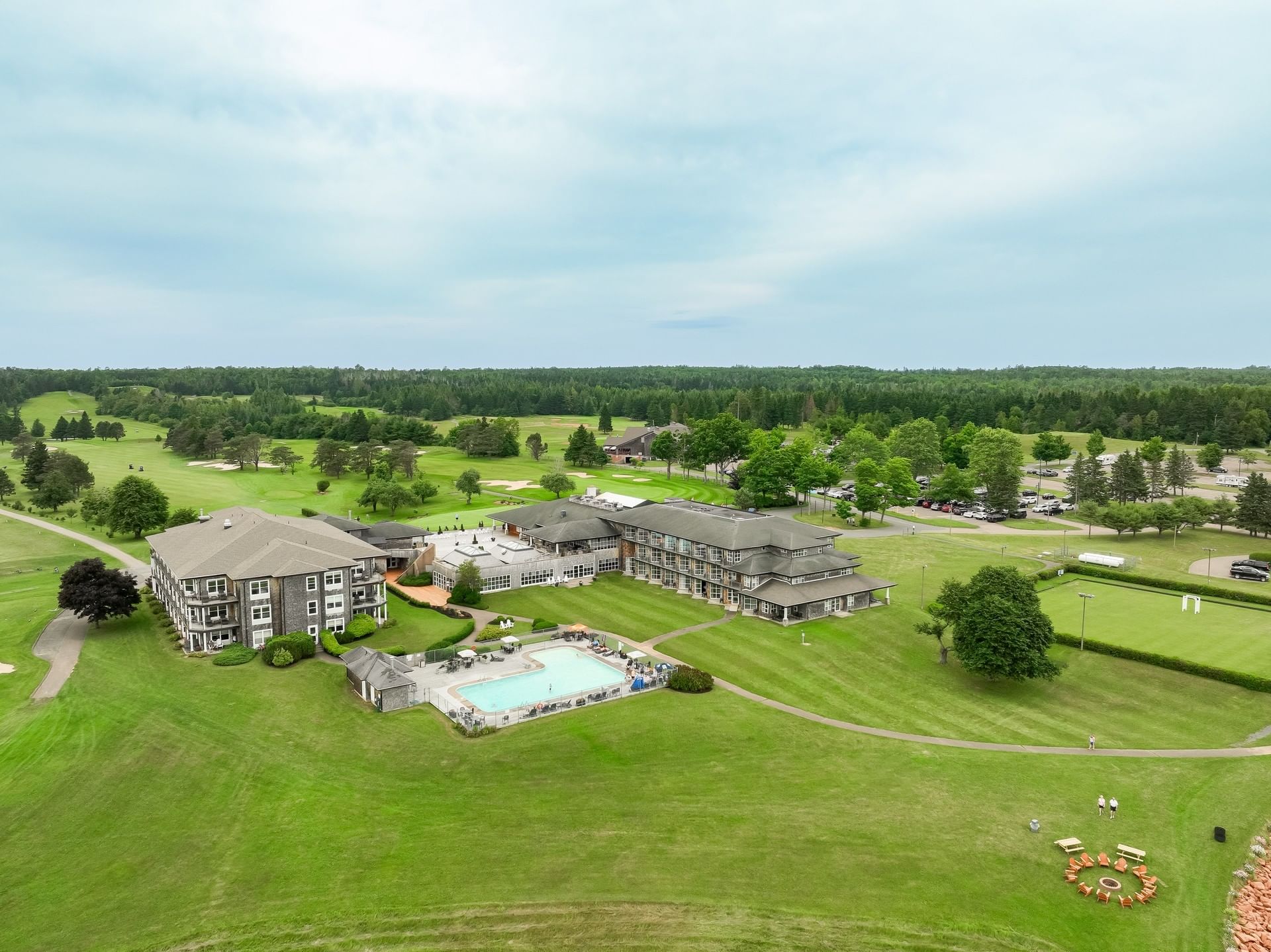 Aerial view of a resort with a pool by a golf course under a cloudy sky at Rodd Brudenell River Resort
