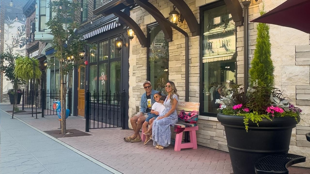 Family sitting on a bench enjoying the outdoor atmosphere of a charming street.