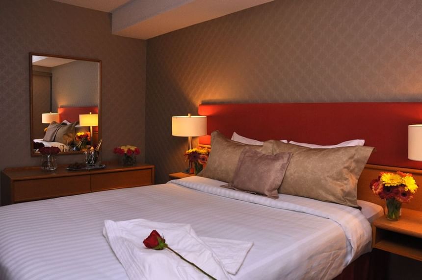 Une rose sur un lit dans la Suite Supérieure du Cartier Place Suite Hotel