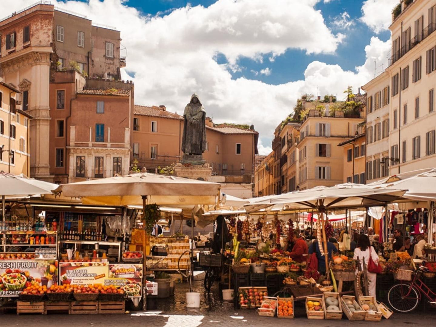 Bustling Campo de Fiori market framed by historic buildings under a bright sky near The Guardian Hotel