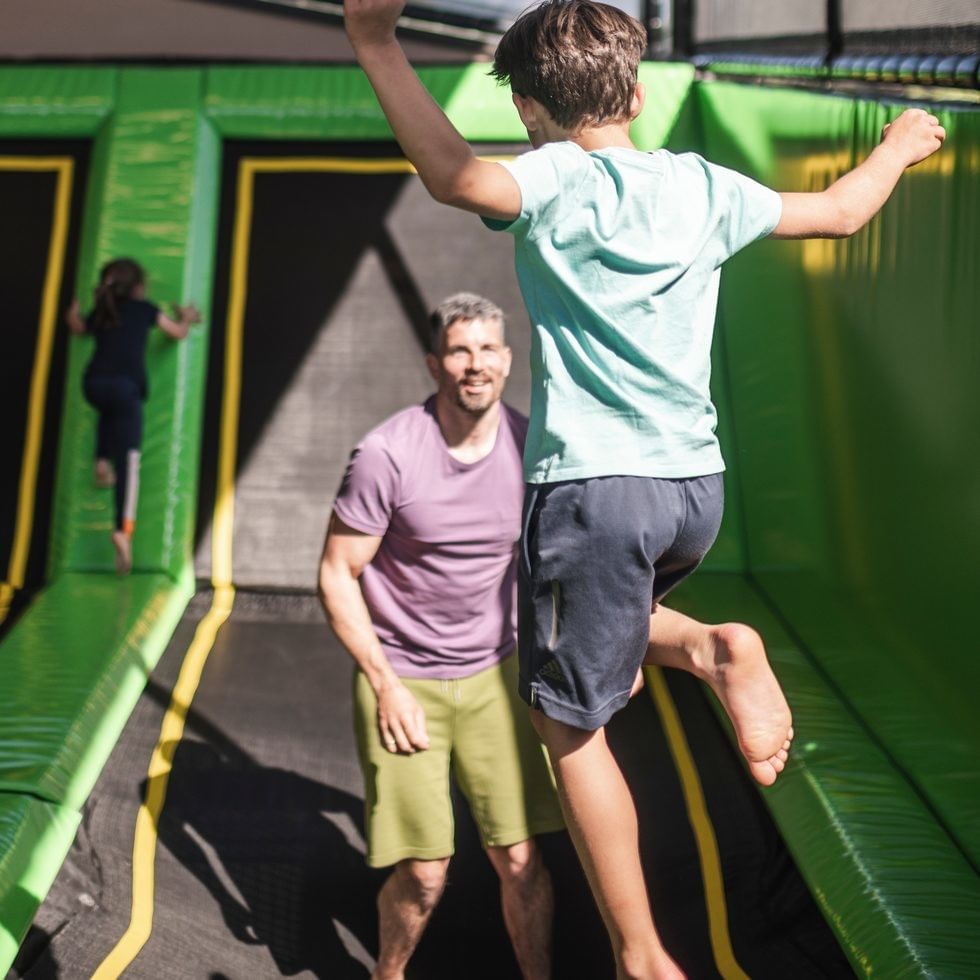 Child jumping on trampoline with adult at Falkensteiner Family Resort Sicily