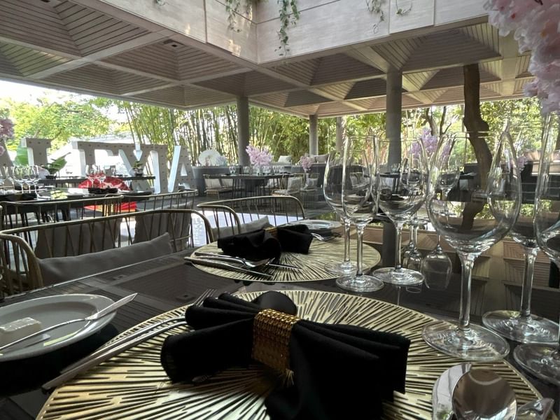 Elegantly set dining table with gold plates and black napkins at Grand Fiesta Americana Sumiya Cuernavaca in Jiutepec.