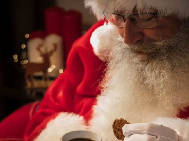 Man dressed as Santa eating a cookie with a cup of coffee at Santa's Brunch.
