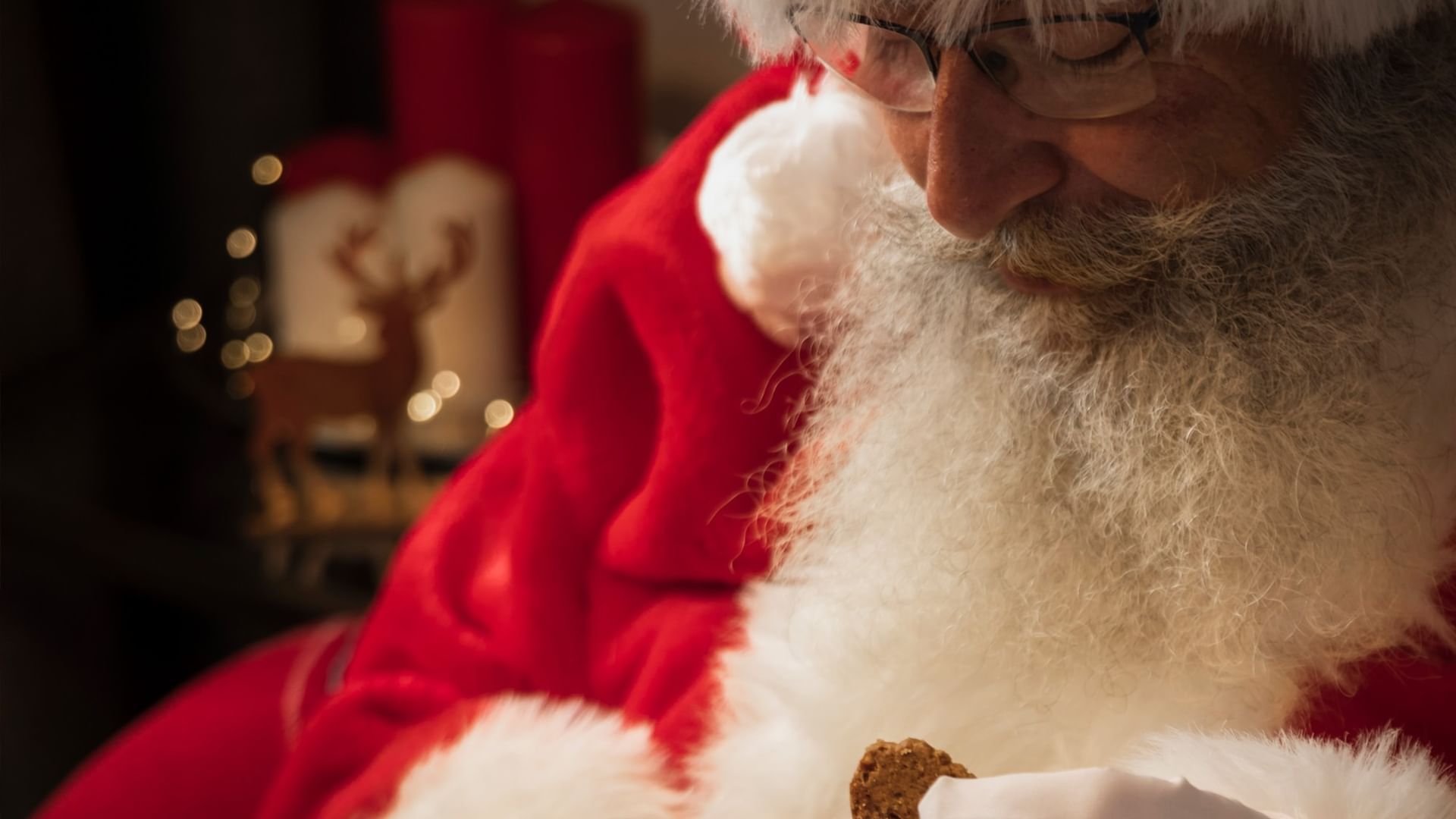 Man dressed as Santa eating a cookie with a cup of coffee at Santa's Brunch.