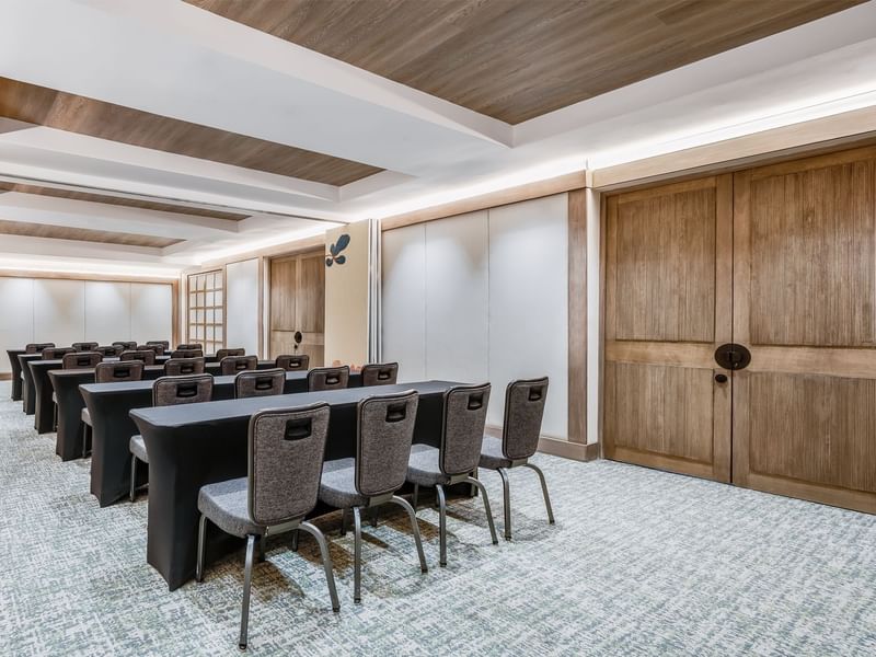 Modern conference room with three rows of tables and chairs, soft lighting, and carpeted floor at Grand Fiesta Americana