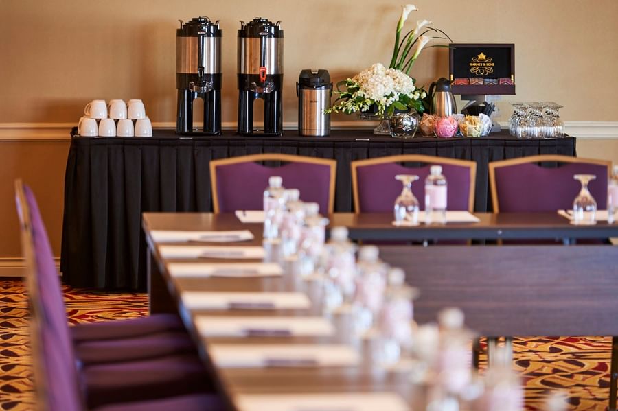 Coffee urns on a black cloth table by white cups under soft light at Warwick Denver