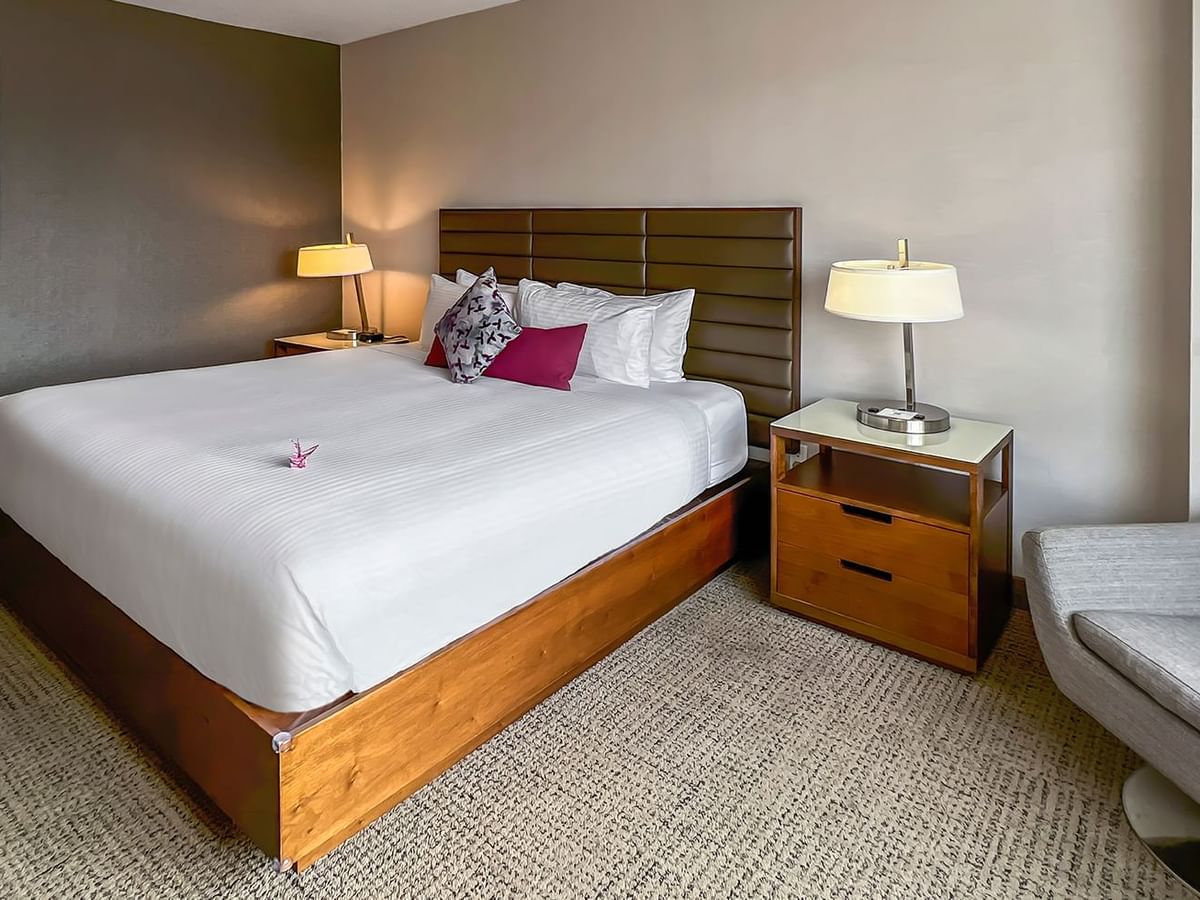 Hotel bedroom with bed, nightstand, chair, and lamp