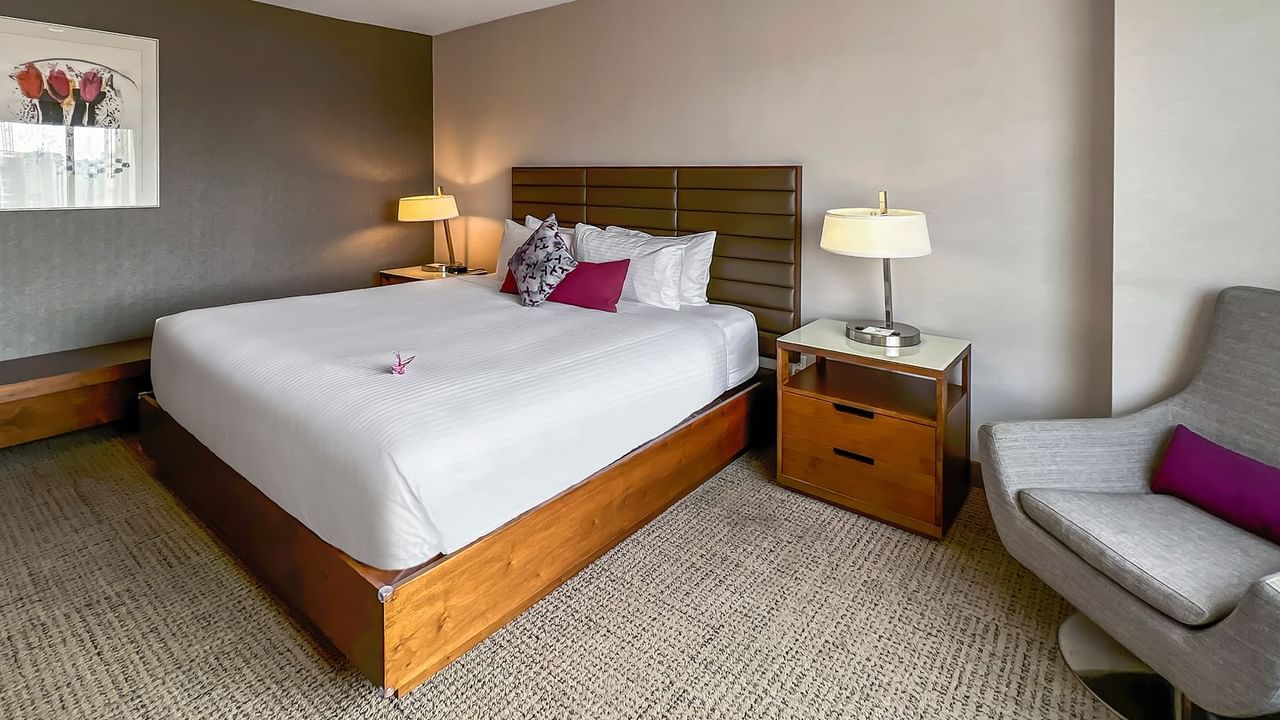 Hotel bedroom with bed, nightstand, chair, and lamp