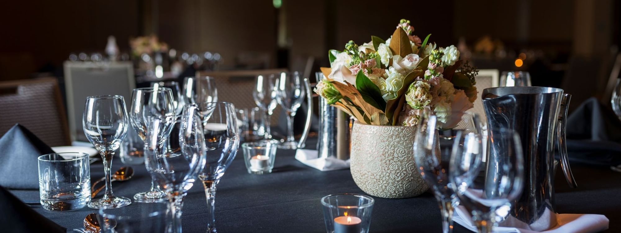 Table arrangement with glasses, flower display and lit candles for an Event at Pullman Sydney Olympic Park