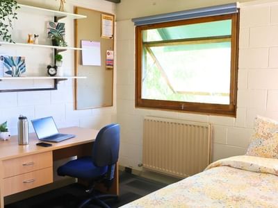 Cozy room with desk, laptop, radiator, and bed at La Trobe University - Units.